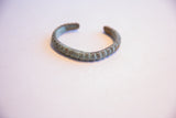 The ribbed texture and green oxidized patina of a vintage African cuff bracelet.