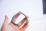 Vintage African cuff bracelet with a textured, oxidized finish held for scale.