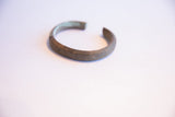The open C-shape and oxidized surface of the handmade vintage African bracelet.