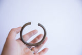 Vintage African oxidized cuff bracelet held in hand, revealing its natural patina.