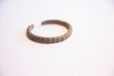 Angled view of the vintage African cuff bracelet showing its segmented, oxidized surface.