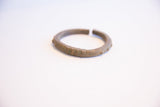A vintage African cuff bracelet's profile showing its textured surface and opening.