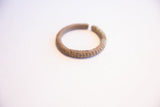 The circular form and textured, oxidized patina of a vintage African cuff bracelet.