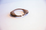 The curved form and time-softened brown patina of a collectible Yoruba rattle bracelet.