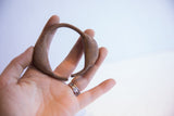 Vintage Yoruba dance bracelet held in hand to show its scale and patina.