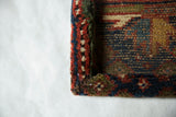 Textured wool pile and wrapped corner of an antique Kurdish Hamadan rug art piece.