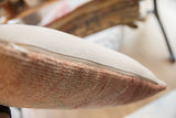 Zipper closure on vintage rug fragment pillow with light beige fabric and textured reddish pile.