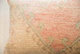Hand-knotted texture of vintage rug fragment pillow with muted coral pink and sage green.