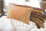 Stacked hand-knotted vintage rug fragments with muted earthy colors and geometric patterns.