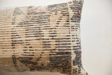 Textured hand-knotted weave detail of vintage rug fragment pillow, showing muted neutral and rust tones.