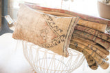 Textured vintage pillow with geometric pattern and striped edge in muted tones.