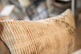 Vintage rug fragment pillow showing woven edge texture with subtle earth tones.