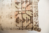 Worn pile texture of a vintage rug fragment pillow in cream, brown, faded coral, and sage.