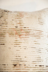 Textured woven surface of vintage rug fragment pillow, with muted green and brown dashes.