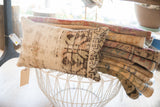 Textured side of a vintage rug fragment pillow with muted cream and brown geometric pattern.