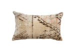 Vintage rug fragment pillow showing an abstract pattern in earthy tones of beige, brown, and sage.