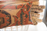 Antique Bijar rug fragment pillow showcasing tribal geometric motifs in rust, beige, green, and blue.