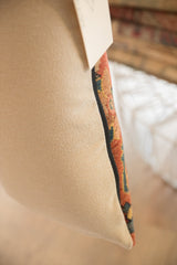 Pillow side with beige back fabric, black piping, and antique Bijar fragment.