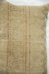 Detailed view of the vintage rug pillow's woven texture with beige, orange, and brown geometric patterns.