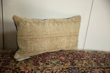 Profile view of a vintage Persian rug fragment pillow showing its woven texture and neutral colors.
