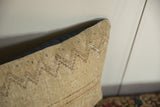 Corner detail of a vintage rug pillow showing the textured weave and dark fabric backing.