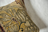 Angled close-up of antique Kerman pillow, saffron yellow art nouveau pattern with red accents.