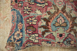 Faded, textured Meshed rug fragment border showing red, blue, ivory, and pink motifs.