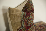 Side profile of an antique Kerman pillow showing the textured wool fragment and neutral backing.