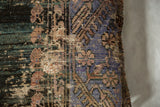 Distressed Anatolian rug fragment pillow revealing faded teal, purple, brown, and beige texture.