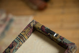 Back corner of the rug fragment art showing the wrapped frame and sawtooth hanger.