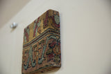Angled view of a rug fragment art piece showing its deep profile and textured antique Kerman wool pile.
