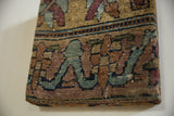 Angled view of the antique rug art's wrapped corner showing its storied wool texture.