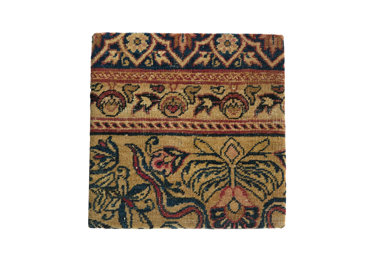 A square decorative cork board featuring an antique Kerman rug with Art Nouveau floral motifs in blue and muted red.
