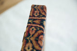 Side profile view of the thick decorative board wrapped in an antique Kerman rug fragment.