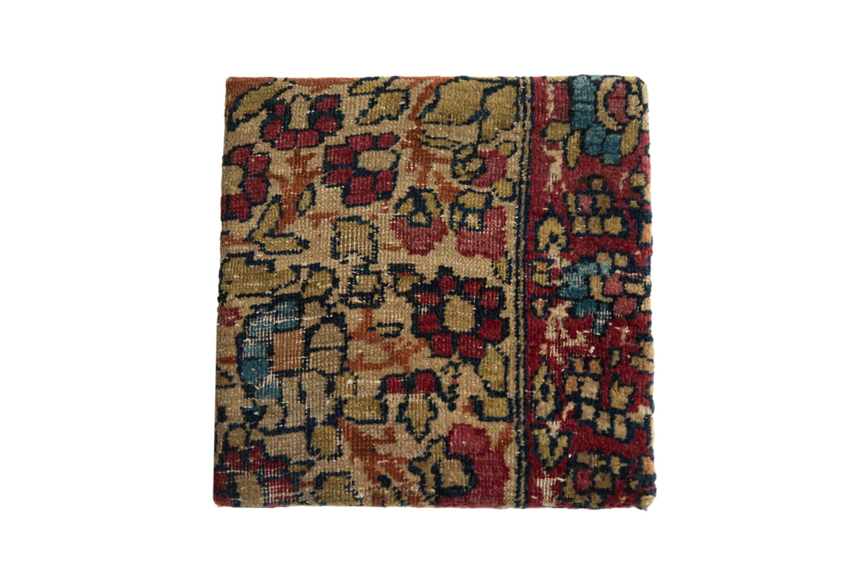 Decorative cork board using an antique Kerman rug fragment with red and blue floral petals.