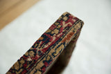 The thick edge of the decorative board wrapped in a textured antique Kerman rug fragment.