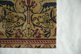 Corner of an antique Kerman fragment showing the woven texture and serpent border.