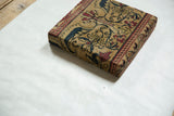 Three-quarter view of a decorative cork board wrapped in an antique Art Nouveau Kerman rug fragment.