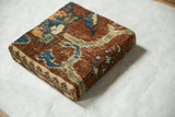 A corner view of the decorative cork board, showing the thick profile and antique rug fragment texture.
