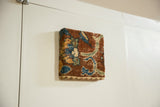 Angled view of the antique rug fragment art, highlighting its woven texture and gallery depth.