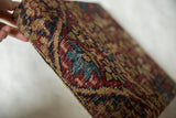 Antique Kerman rug fragment edge reveals intricate cochineal red and sapphire blue weave.