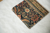 Angled profile view of the decorative cork board, showing its thickness wrapped in antique rug textile.