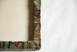 Mitered corner detail of a cork board framed with a textured antique Kerman rug fragment.
