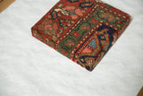 Angled profile of the antique rug fragment art showing its wrapped corner and woven texture.
