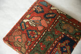 Angled detail of the antique Kurdish rug art, highlighting the thick profile and green geometric border.