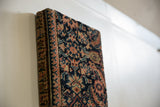 Angled side view of the decorative art board, showing the texture and thickness of the antique rug fragment.