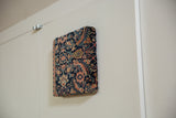 Angled view of the decorative cork board, showing the thick profile and antique Fereghan textile.