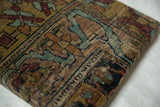Corner view of the antique Kerman rug fragment's time-worn texture and silk-like wool pile.