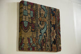 Angled view of antique Kerman rug fragment art, showing its texture and dimensional depth.
