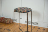 Reclaimed side table featuring an antique Persian rug fragment top with navy and saffron yellow details.